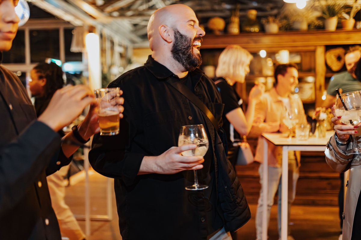 Gast geniet lachend van een drankje tijdens een evenement